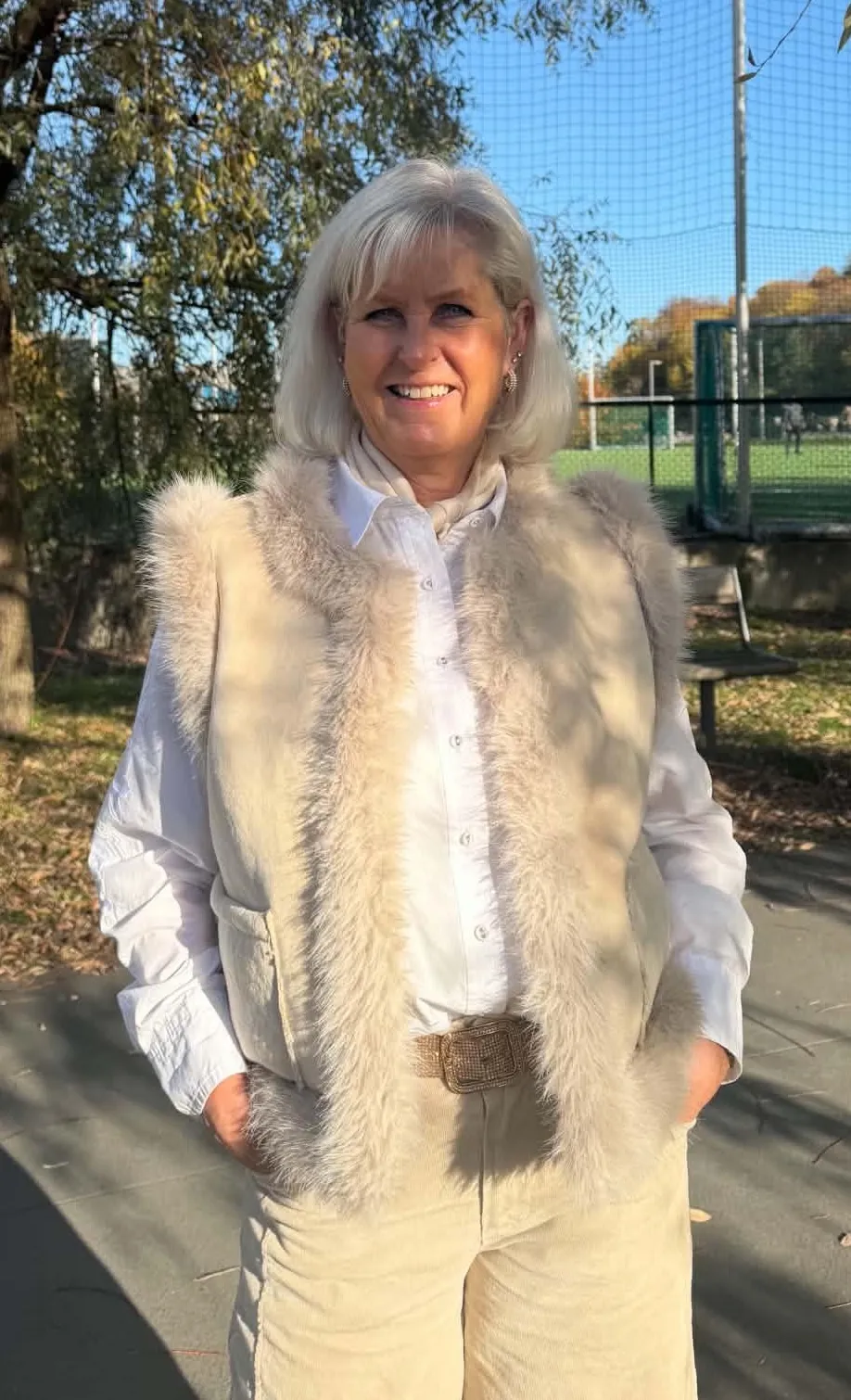 Kvinne i camel ponchojakke med hette i en høstpark